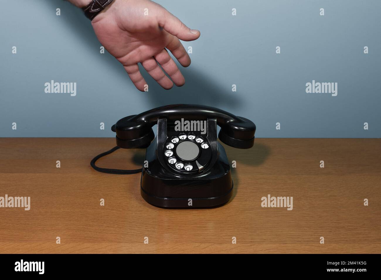 Die Hand geht ans Telefon. Altes Telefon auf einem Holztisch, Stockfoto
