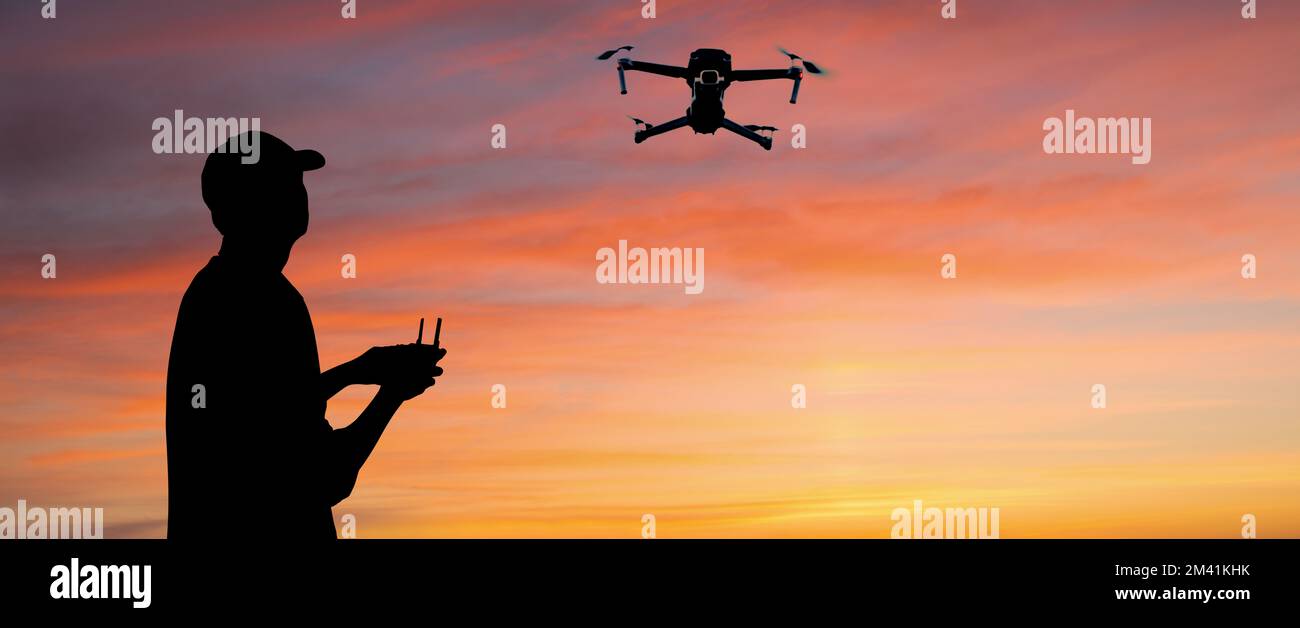 Silhouette eines Mannes steuert eine Drohne bei einem Sonnenuntergang Hintergrund Stockfoto