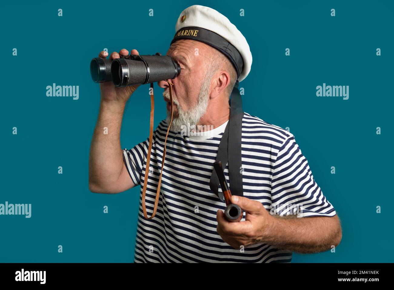 Ein alter Seemann blickt in die Ferne mit einer Rauchpfeife und einem Fernglas Stockfoto
