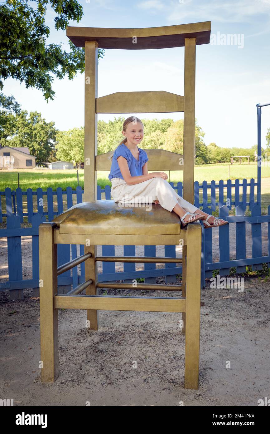 Mädchen-Teenager-Porträt. Im Sommerpark spazieren gehen. Er sitzt auf einem riesigen Stuhl Stockfoto