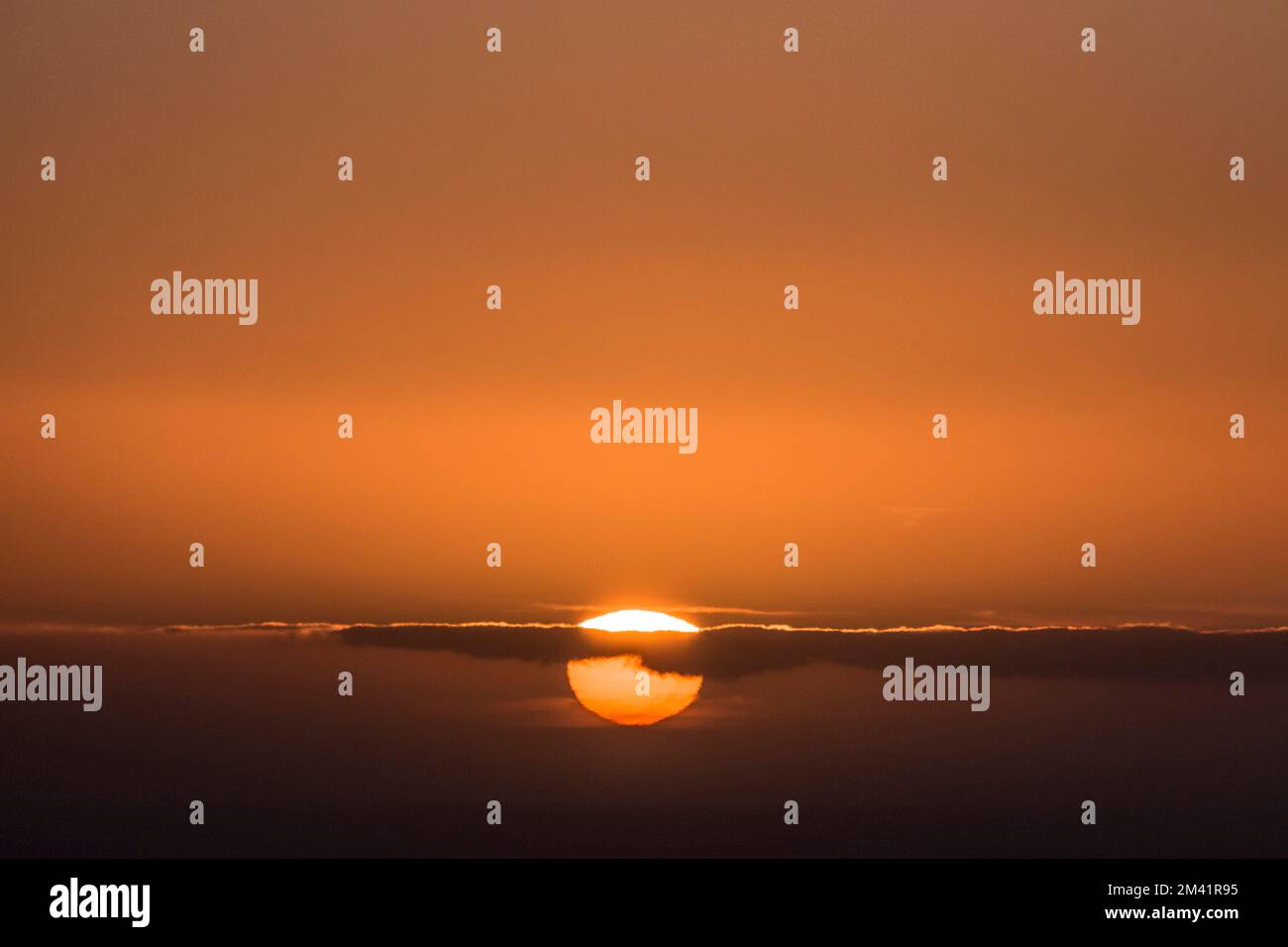 Ein wunderschöner Sonnenuntergang in dunkelorangefarbenen Farben mit der Sonne unter der Skyline Stockfoto