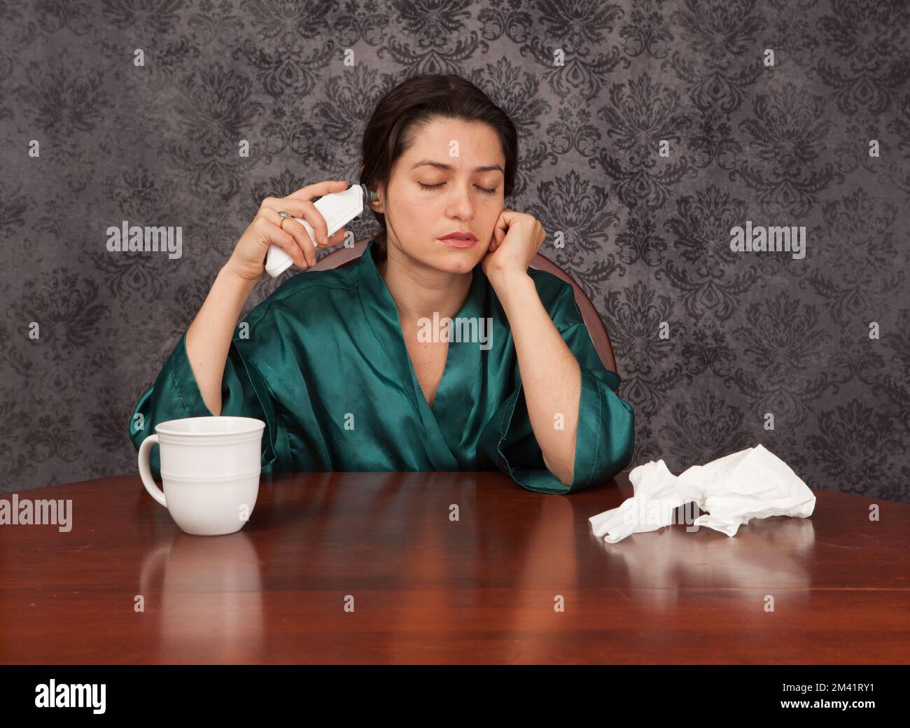 Frau leidet unter Kopfschmerzen und Grippe Symptome zu Hause mit einer Tasse Kaffee und Geweben ihre Temperatur unter Stockfoto