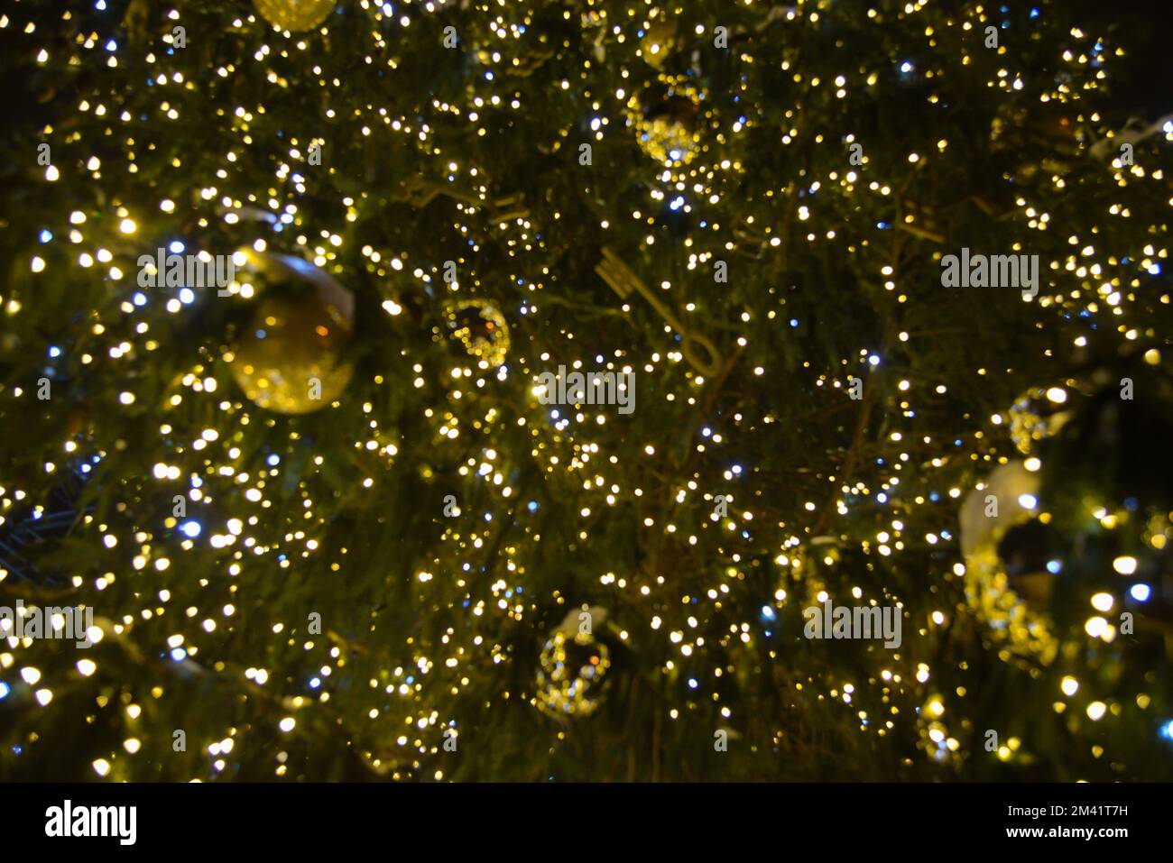 Unscharfer Weihnachtsbaum mit Weihnachtsbeleuchtung und Dekorationen. Stockfoto