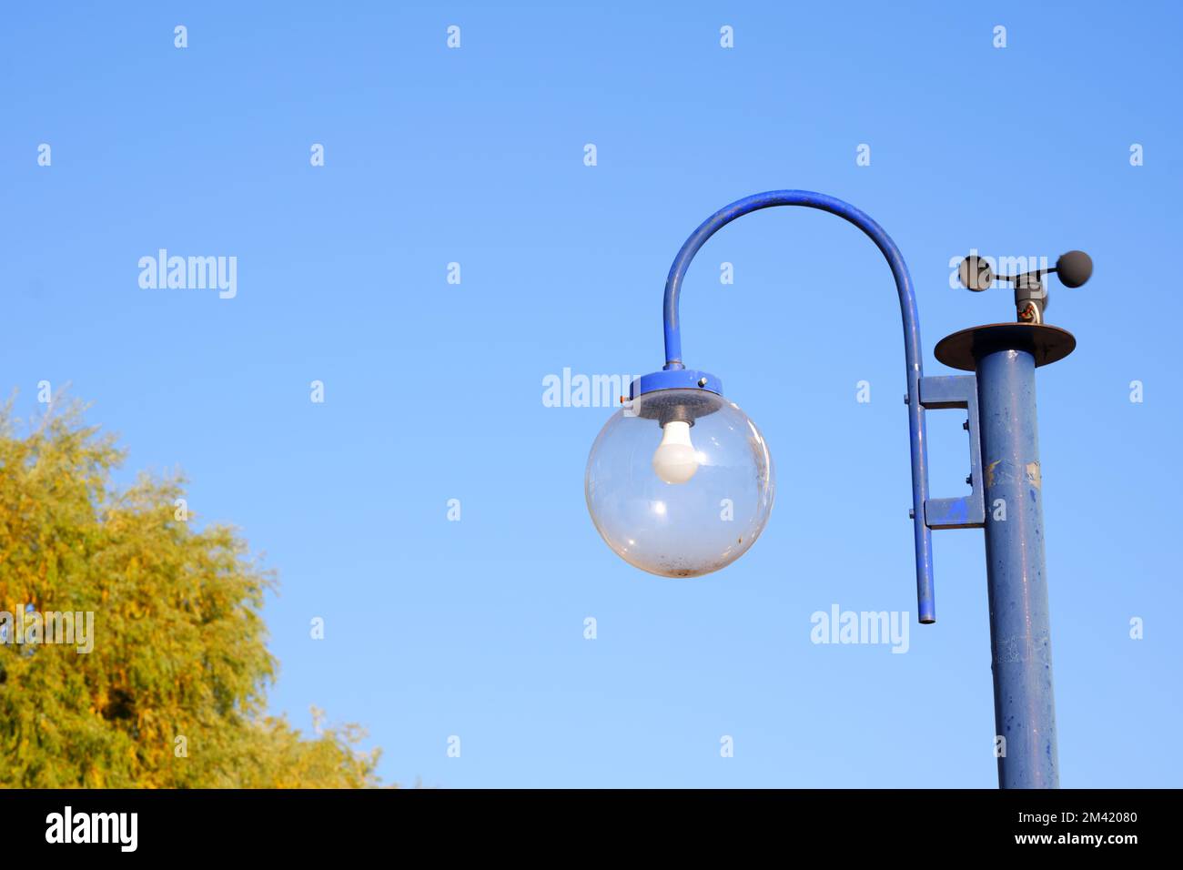 Blaue Straßenlampe mit Anamometer und blauem Himmel im Hintergrund an einem sonnigen Sommertag Stockfoto