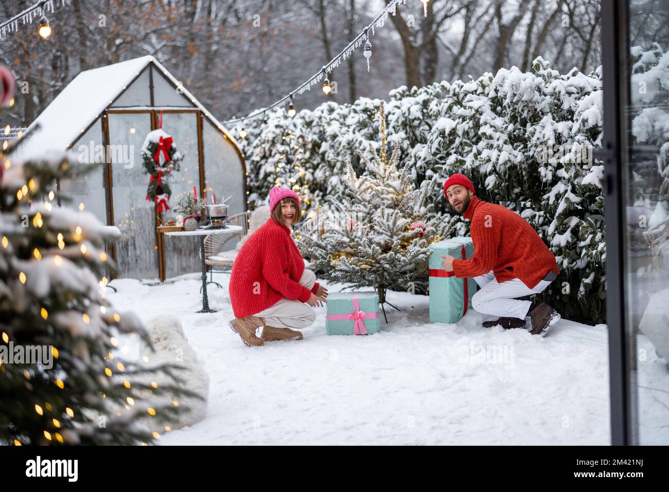 Ein junges Paar schmückt den Weihnachtsbaum im Garten Stockfoto