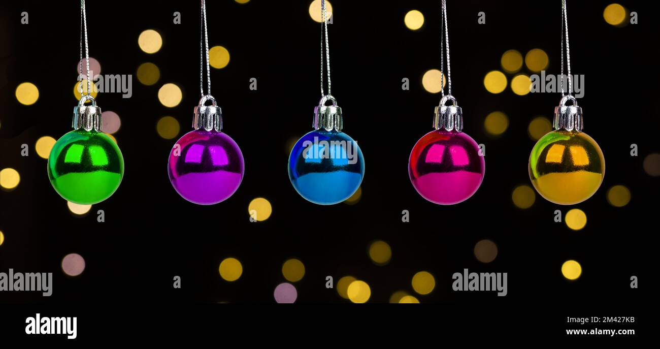 Weihnachtskugeln, kleine Kugeln in verschiedenen Farben auf dunklem Hintergrund mit Weihnachtslichtern. Hochwertiges Foto Stockfoto