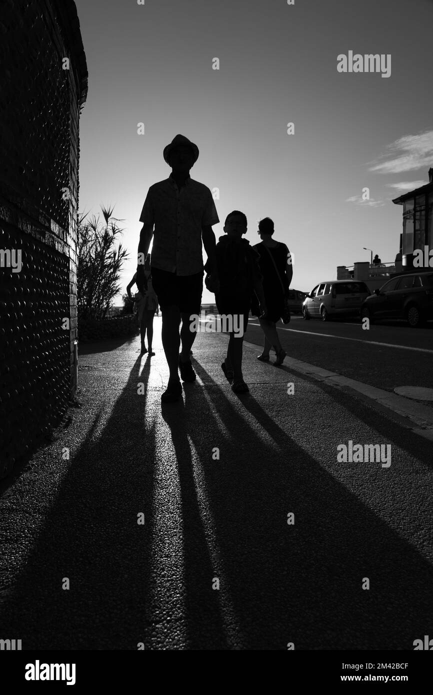 Lange Schatten von einer Familie, die von der untergehenden Sonne beleuchtet wird Stockfoto