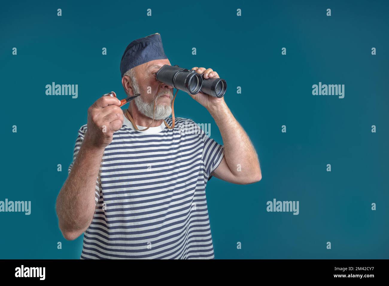 Ein alter Seemann mit einer Rauchpfeife und einem Fernglas blickt in die Ferne Stockfoto