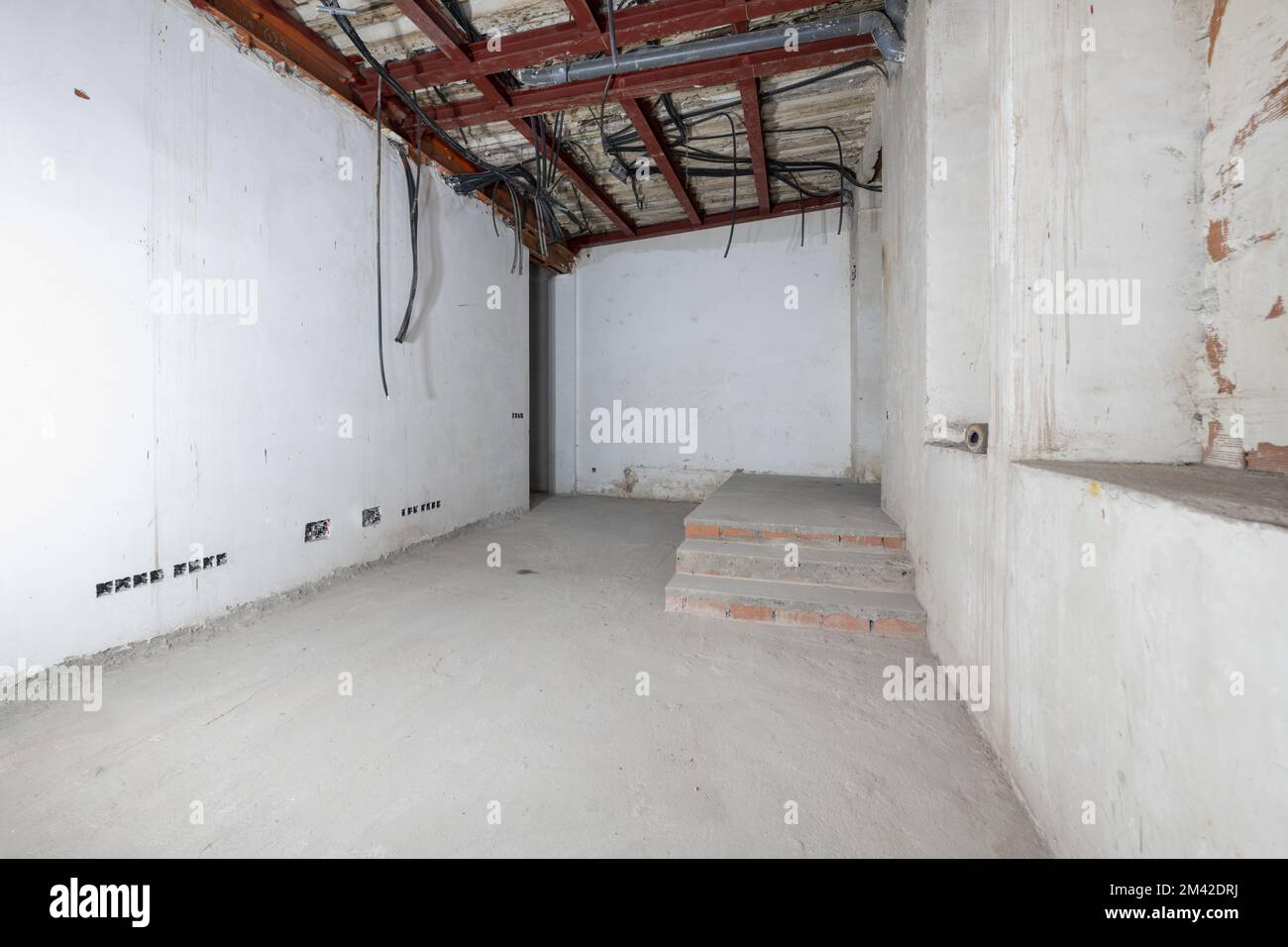 Rohraum mit verputzten Wänden im renovierten Gebäude mit Betonböden, Wellkunststoffrohren zur Leitung von Elektrokabeln Stockfoto