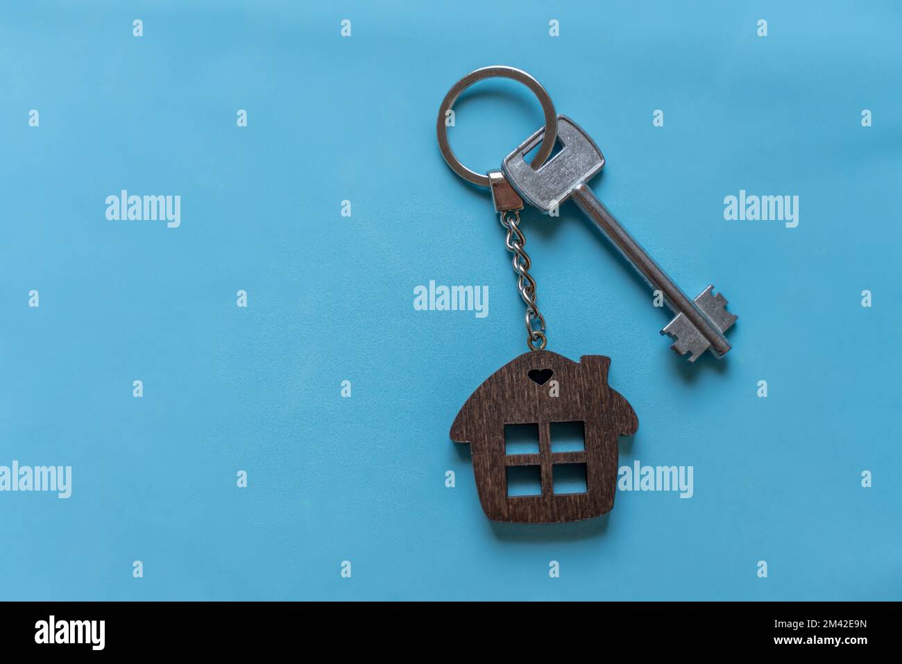 Schlüssel mit Schlüsselanhänger auf blauem Hintergrund. Immobilienmakler. Ich kaufe ein Haus, eine Wohnung. Stockfoto