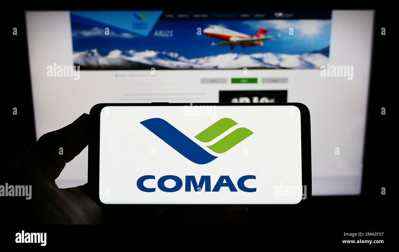 Person, die ein Smartphone mit dem Logo der Commercial Aircraft Corporation of China (COMAC) auf dem Bildschirm vor der Website hält. Konzentrieren Sie sich auf das Display des Telefons. Stockfoto