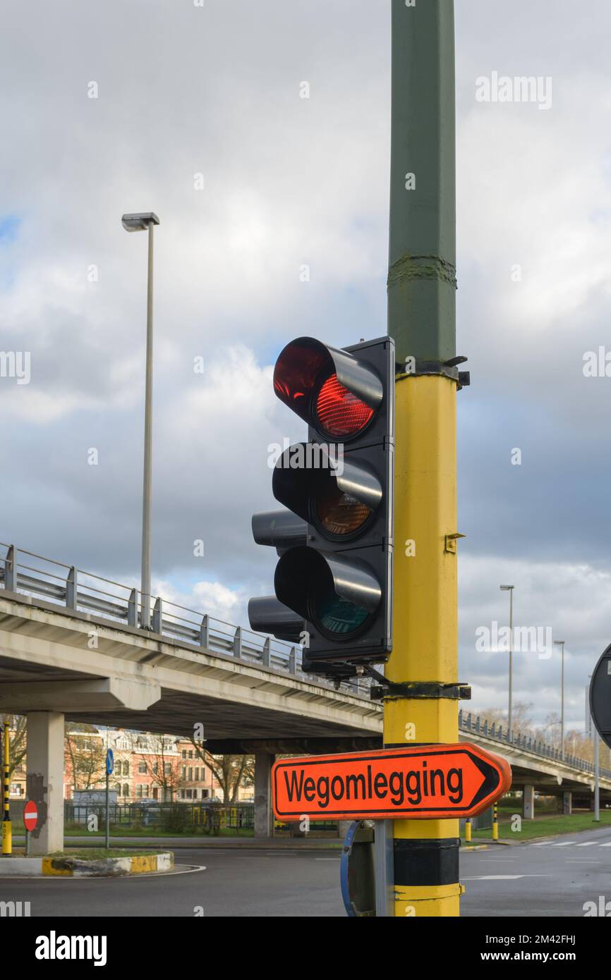 Straßenschild der Umgehungsstraße Richtung Wegomlegging - Inschrift auf Niederländisch. Ampel mit rotem Signal an der Kreuzung Stockfoto