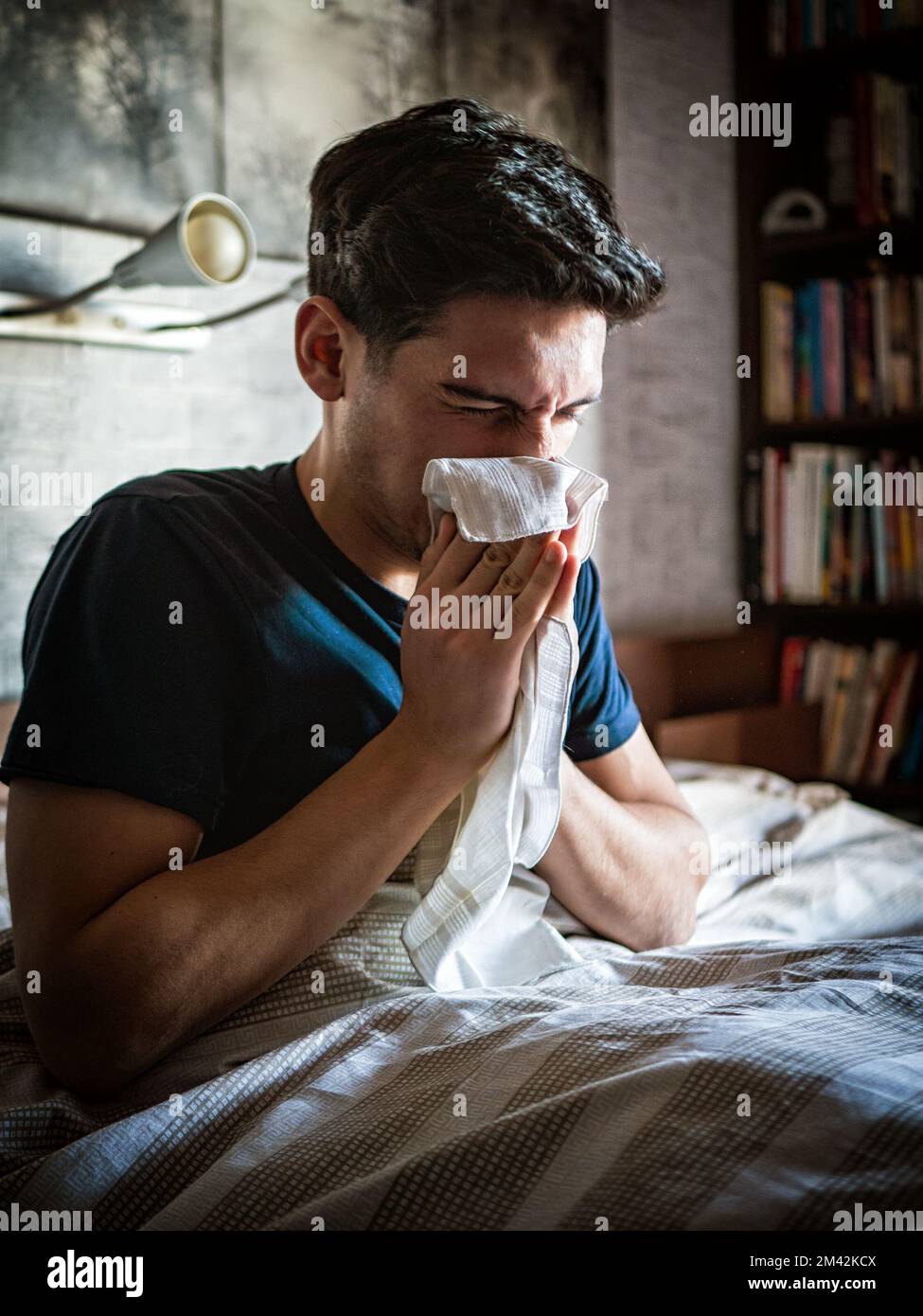 Junger Mann, der sich die Nase mit Taschentuch putzt Stockfoto