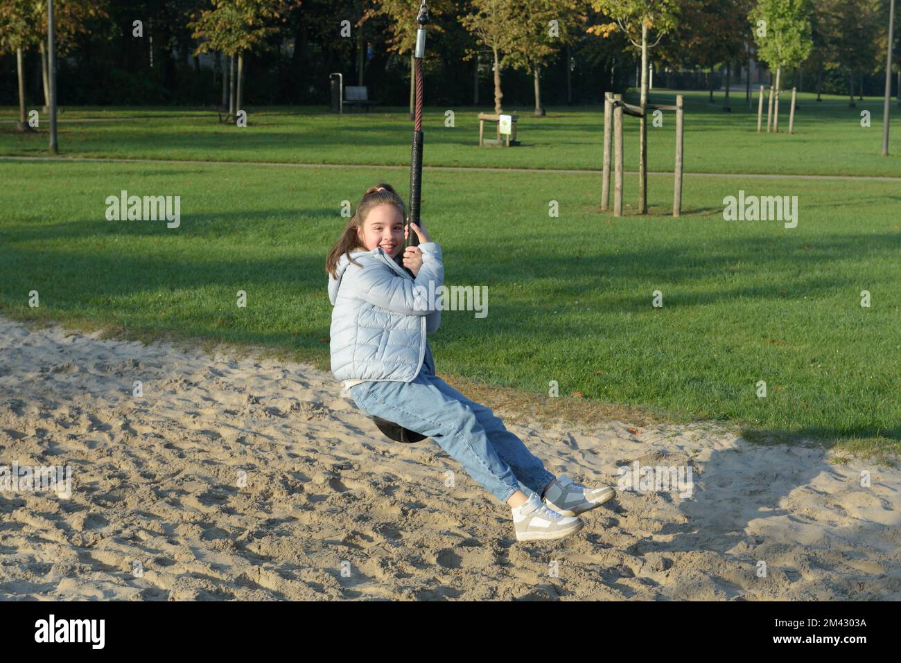 Spaß im Herbst im Freien. Ein junges Mädchen, das auf einem Bungee auf dem Spielplatz reitet Stockfoto