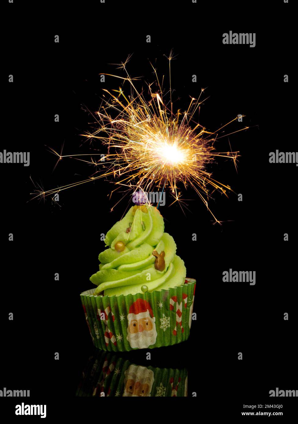 Lustiger weihnachtlicher Cupcake, Kuchen mit goldenem Glitzer isoliert auf schwarzem Hintergrund. Stockfoto