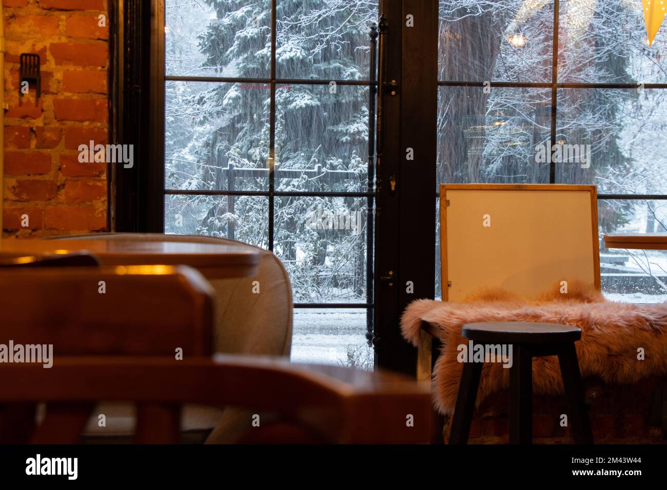 Café mit Blick auf den Schneefall vom Fenster in der Ukraine, das Innere des Cafés mit Holzmöbeln Stockfoto