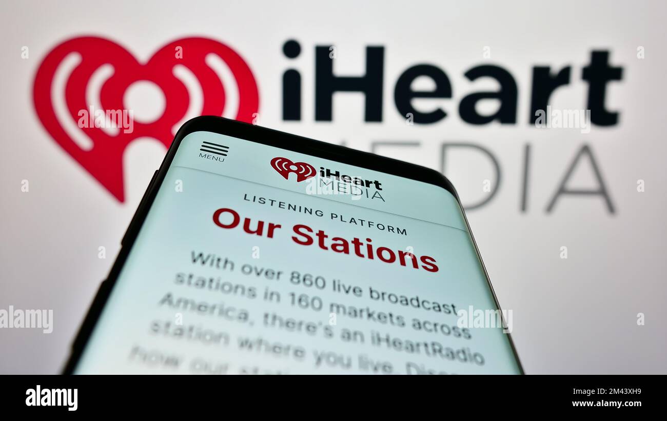 Mobiltelefon mit Webseite des US-amerikanischen Massenmedienunternehmens iHeartMedia Inc. Auf dem Bildschirm vor dem Unternehmenslogo. Fokus auf oberer linker Seite des Telefondisplays. Stockfoto