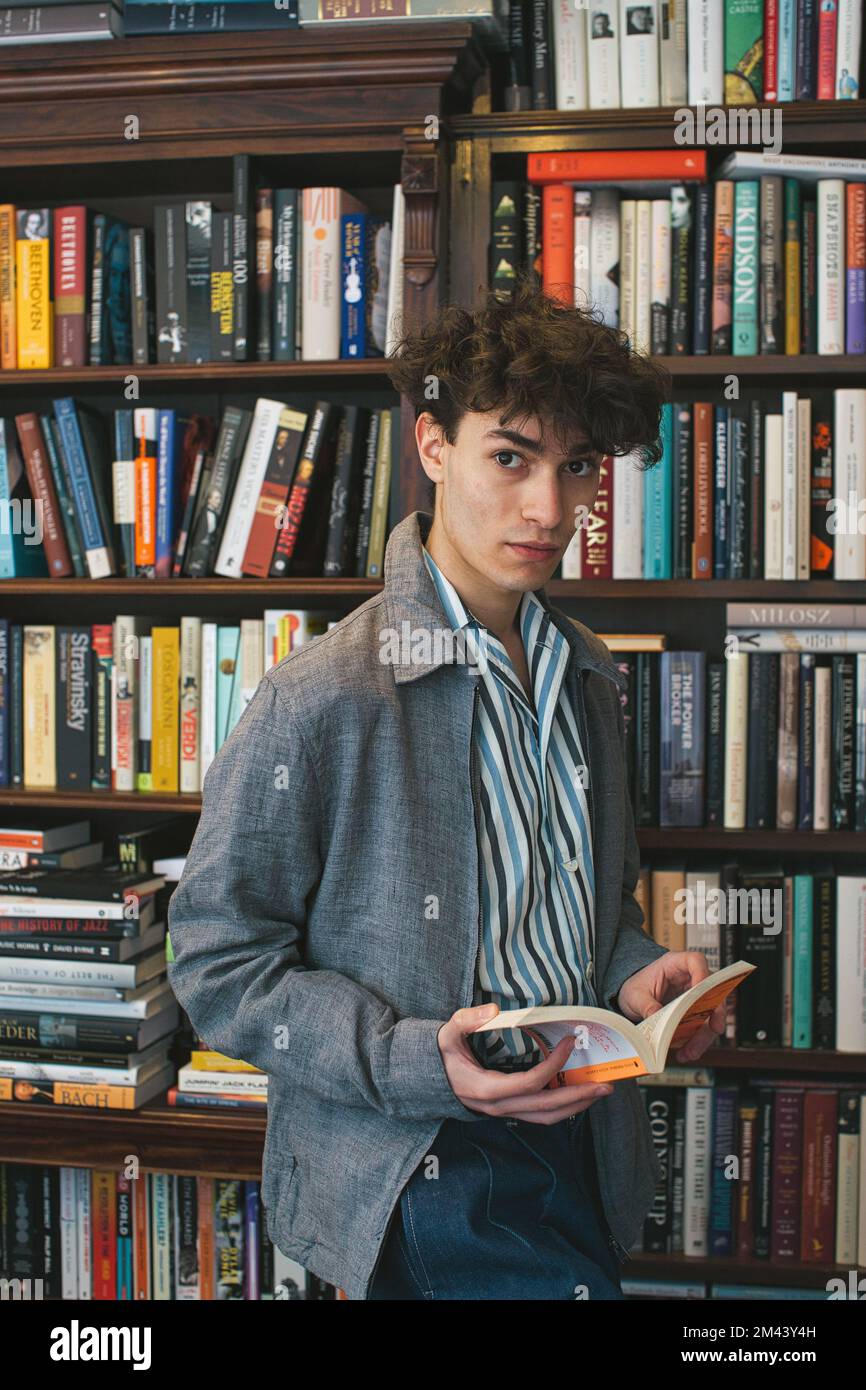 Junger Mann hält Buch in der Buchhandlung Stockfoto