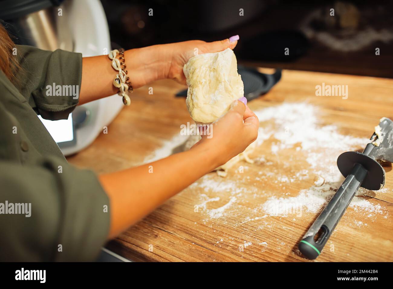 Die Hände einer Frau kneten den viskosen Teig durch Nahaufnahme der Hände. Kochen auf Holzablagefläche zu Hause. Traditionelles Gebäck backen. Stockfoto