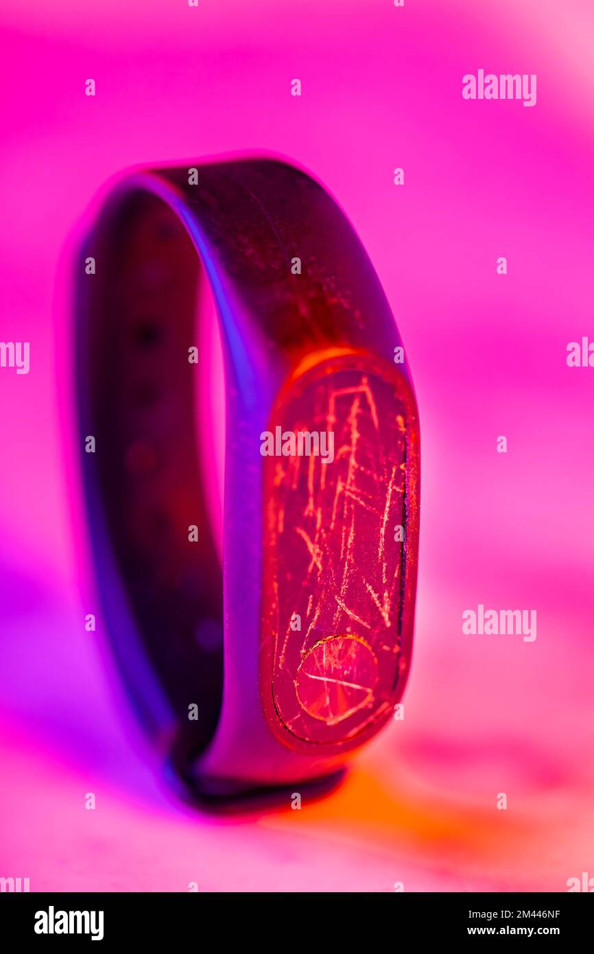 Smartwatch mit kaputtem Display im Neonlicht. Fitness-Tracker mit rissigem Bildschirm. Reparaturservice Stockfoto