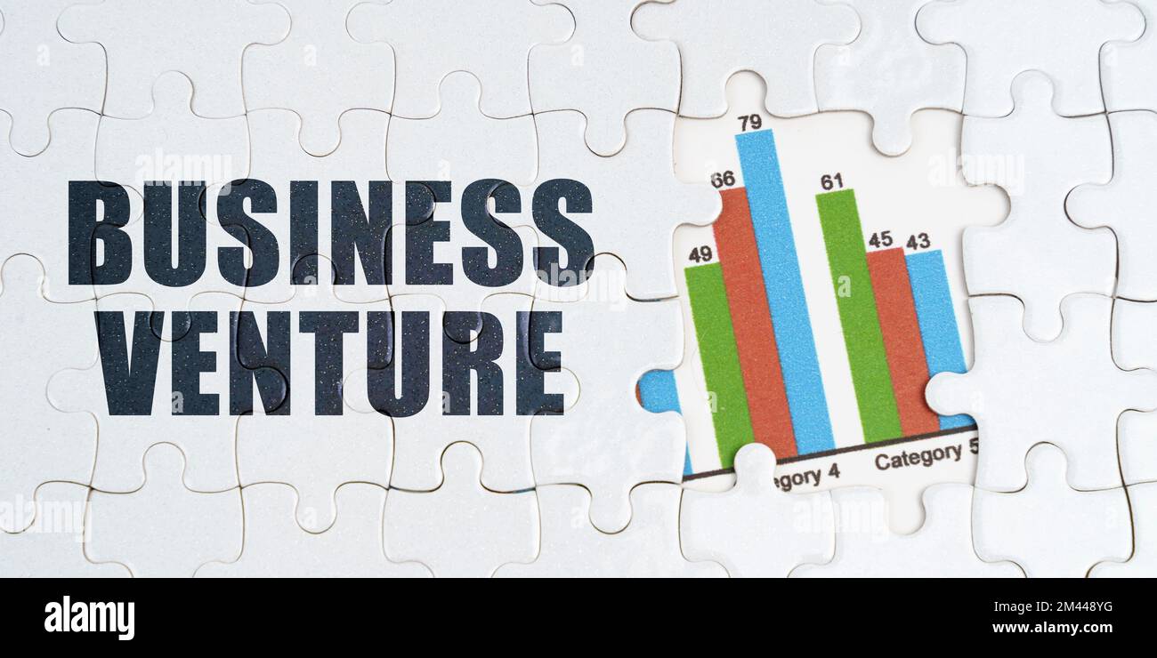 Wirtschaft und Geschäftskonzept. Auf weißen Rätseln steht die Inschrift "Business Venture". Finanzdiagramm im Fenster zwischen den Rätseln Stockfoto