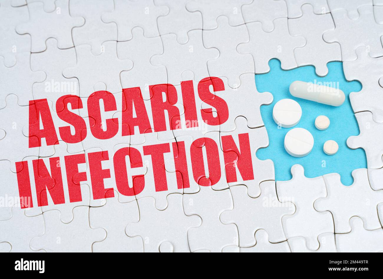 Medizinisches Konzept. Auf den Rätseln ist eine Inschrift - Ascaris-Infektion, auf einem blauen Hintergrund Pillen. Stockfoto
