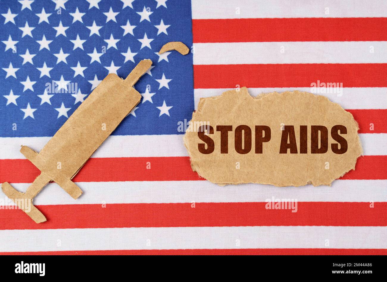 Medizinisches Konzept. Auf der US-Flagge befindet sich eine Pappfigur einer Spritze und ein zerrissener Karton mit der Aufschrift „STOP AIDS“ Stockfoto