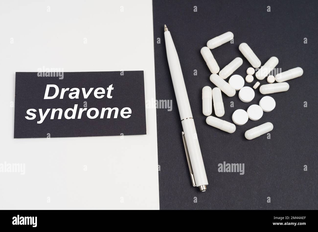 Medizinisches Konzept. Auf einer weißen und schwarzen Oberfläche sind Pillen, ein Stift und ein Schild mit der Inschrift - Dravet-Syndrom Stockfoto