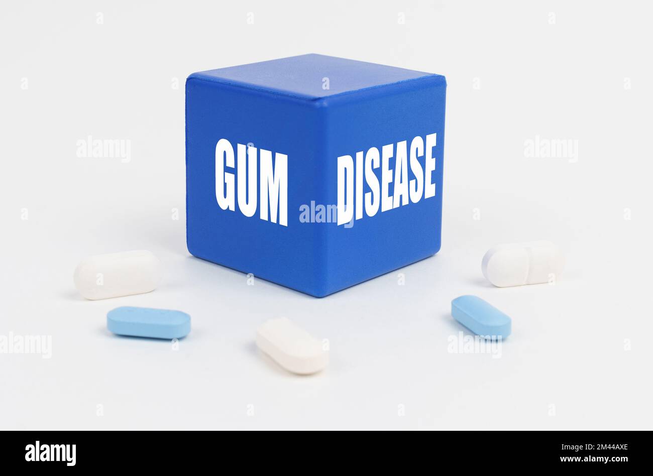 Medizin und Gesundheitskonzept. Auf einer weißen Oberfläche sind Pillen und ein blauer Würfel, der sagt - ZAHNFLEISCHKRANKHEIT Stockfoto