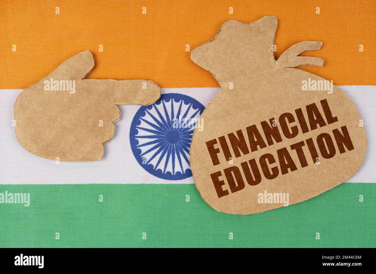 Der Begriff Volkswirtschaft und Wirtschaft. Auf der indischen Flagge, Pappfiguren einer Hand und einer Geldtasche mit der Aufschrift "FINANCIAL EDUCA" Stockfoto