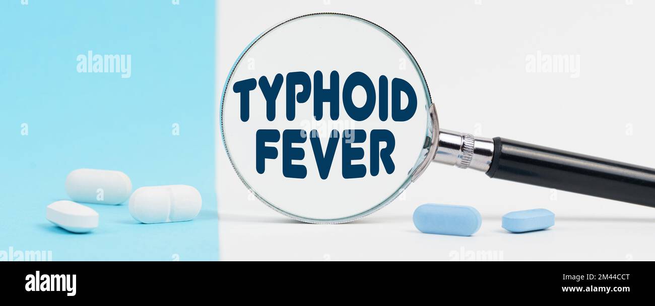 Medizin und Gesundheitskonzept. Auf blauem und weißem Hintergrund gibt es Pillen und eine Lupe, in der es steht - TYPHUS Stockfoto
