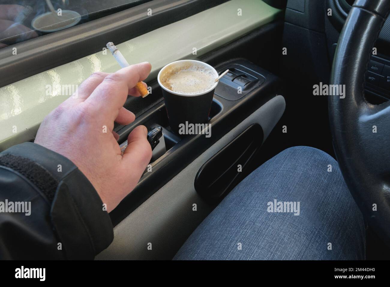 Die Zigarette in der Hand. Einweg-Kaffeebecher aus Papier. Rauchen beim Autofahren. Stockfoto