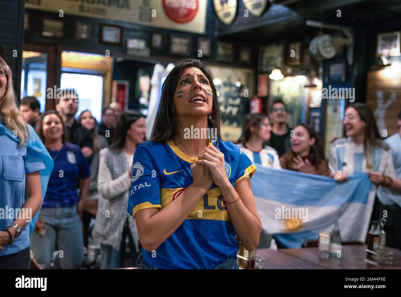 Barcelona, Spanien. 18.. Dezember 2022. Eine Frau in einem Boca Juniors-Trikot singt während des WM-Finales gegen Frankreich die argentinische Hymne. Mindestens 100 Argentinier versammelten sich in der Sonora-Bar in Barcelona, um die argentinische Nationalmannschaft im WM-Finale gegen Frankreich anzufeuern. (Foto: Ximena Borrazas/SOPA Images/Sipa USA) Guthaben: SIPA USA/Alamy Live News Stockfoto