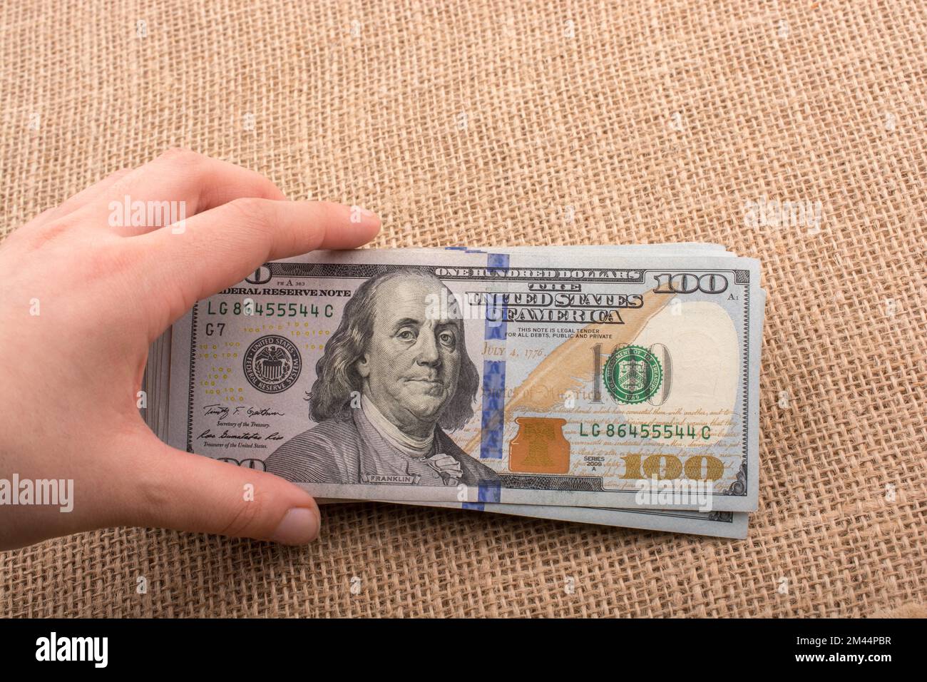 Hand, die Banknote Bündel von US-Dollar auf Leinwand Hintergrund Stockfoto