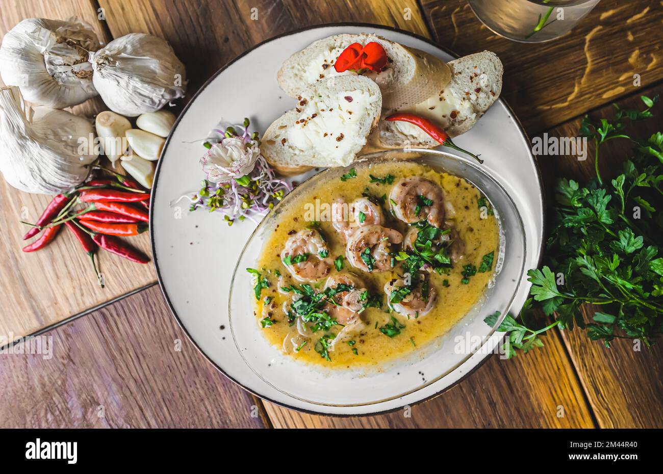 Garnelen in scharfer Sauce serviert mit Brot. Draufsicht. Weiße Platte auf Holztisch. Speisenkonzept des Restaurants. Hochwertiges Foto Stockfoto