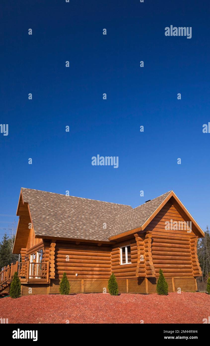 Braunes, rötlich gefärbtes Blockhaus mit braunem und braunem Asphaltschindeldach im Herbst. Stockfoto