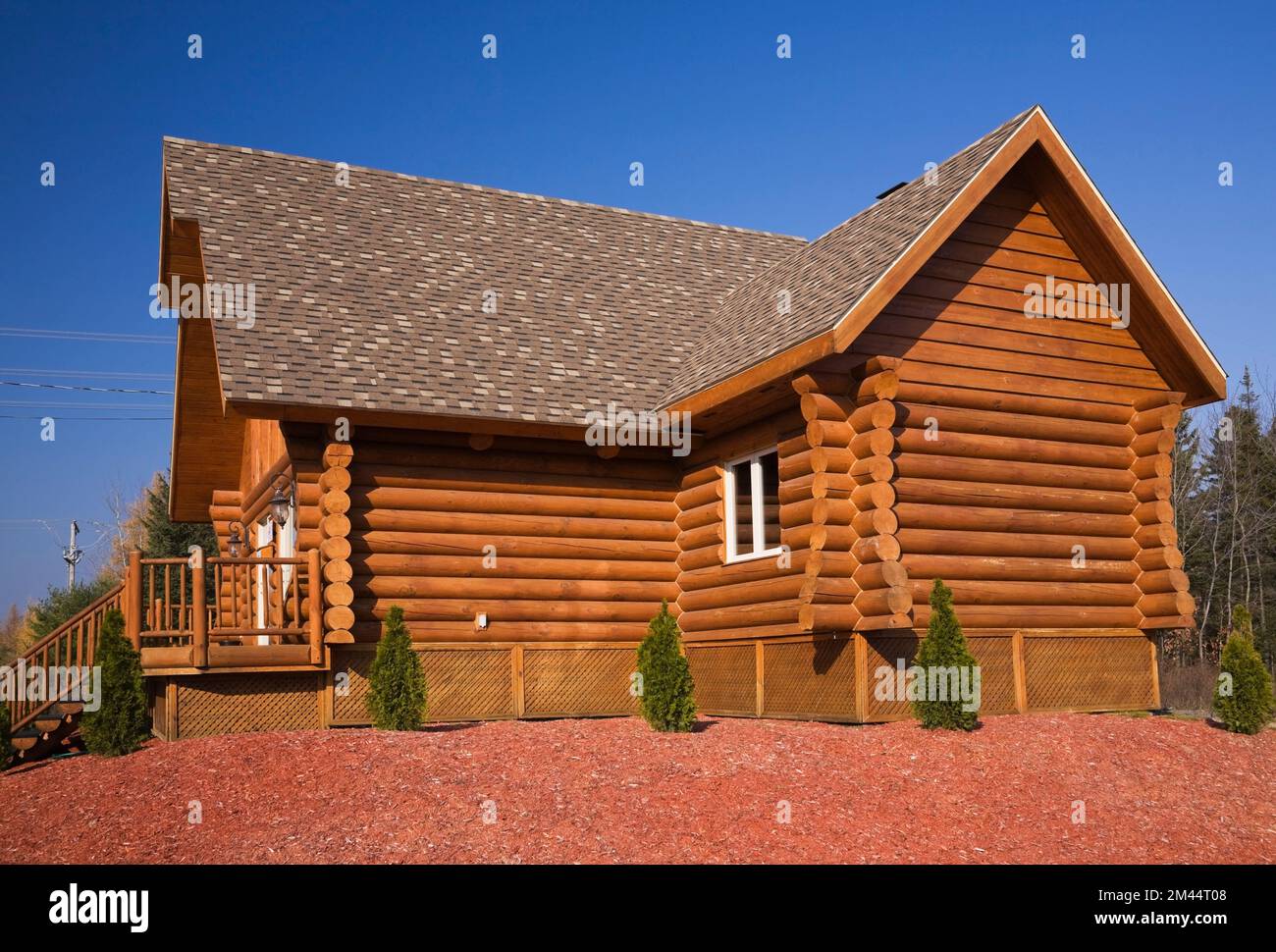 Braunes, rötlich gefärbtes Blockhaus mit braunem und braunem Asphaltschindeldach im Herbst. Stockfoto