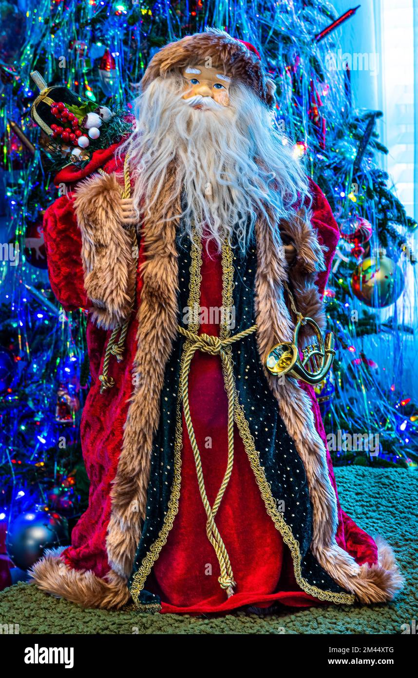 Der Weihnachtsmann steht vor einem dekorierten Weihnachtsbaum. Weihnachtsbälle und andere Weihnachtsdekorationen. Stockfoto