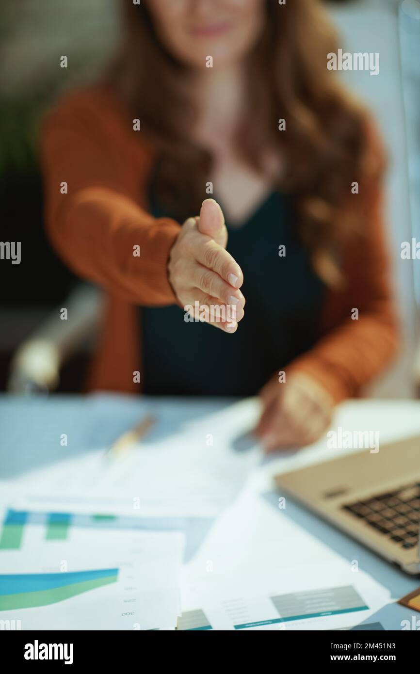 Nahaufnahme der Besitzerin im grünen Büro, die sich die Hand zum Händeschütteln streckt. Stockfoto