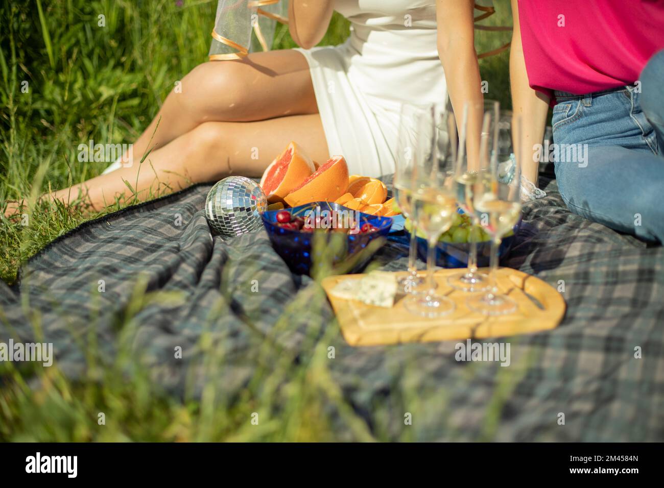 Picknick im Sommer im Park. Essen auf dem Hintergrund von Mädchen. Sektgläser. Details der Erholung im Park. Essen auf der Straße. Obst mimt Getränke. Stockfoto