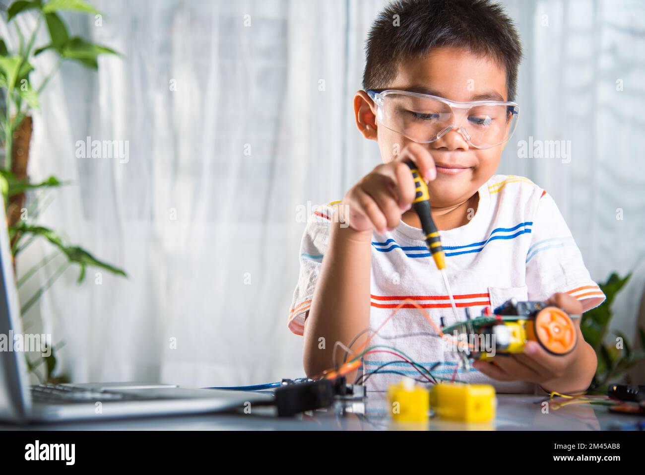 Asiatischer Junge, der zu Hause das Heimprojekt des Arduino-Roboters zusammenführt Stockfoto