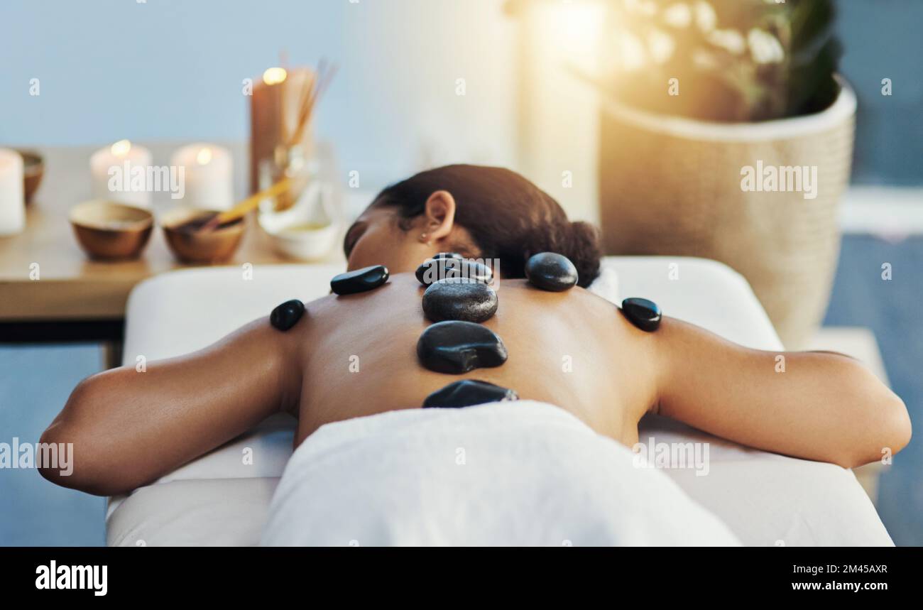 Es ist so eine therapeutische Behandlung. Eine junge Frau, die eine Hot-Stone-Massage in einem Spa bekommt. Stockfoto
