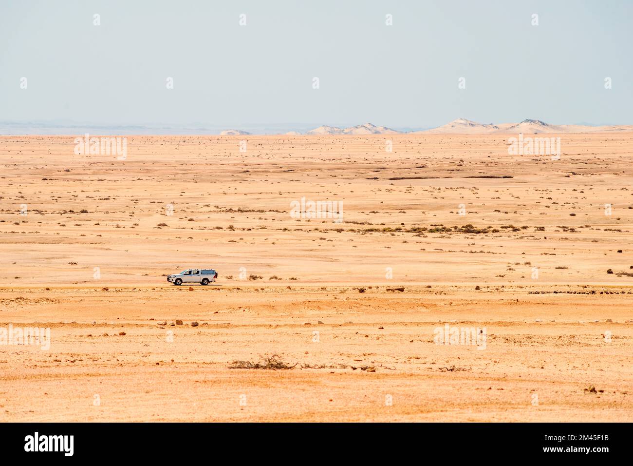 Geländewagen, der sich an sonnigen Tagen auf Schotterstraßen in der endlosen Wüste Namibias bewegt Stockfoto