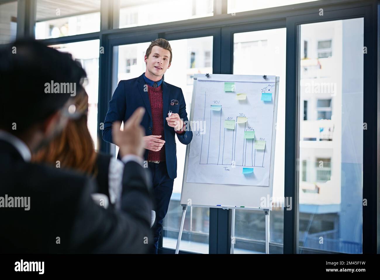 Ja, das sind die Zahlen, die zuschlagen wollten. Ein junger Geschäftsmann, der seinen Kollegen in einem modernen Büro eine Demonstration auf einem Whiteboard vorführt. Stockfoto