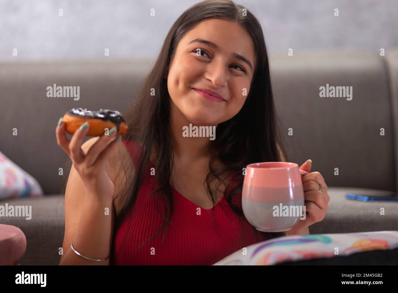 Porträt eines glücklichen Teenagers mit Schokoladentoughnut und Kaffee zu Hause Stockfoto