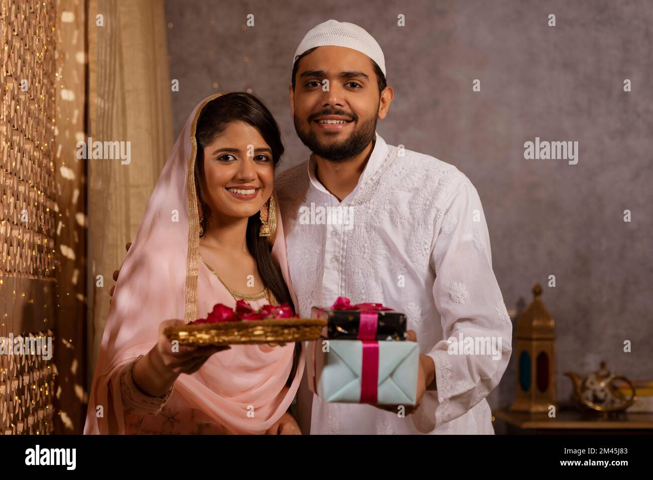 Portrait eines glücklichen muslimischen Paares mit Geschenk und Rosenblättern während Eid-UL-Fitr Stockfoto