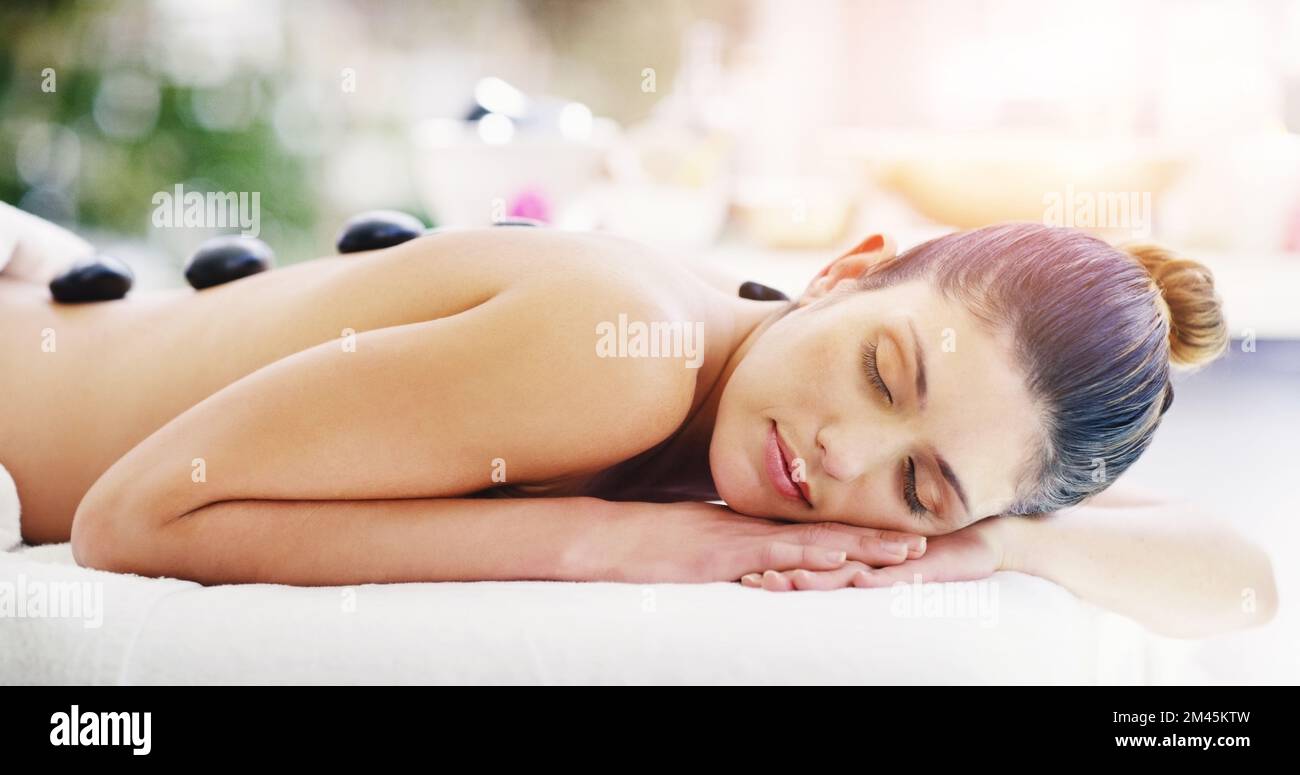 Deine Schmerzen werden von Natur aus verschwinden. Eine junge Frau, die eine Hot-Stone-Massage in einem Spa bekommt. Stockfoto