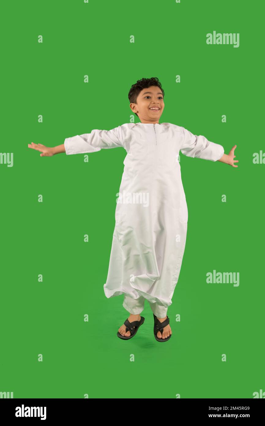 Ein arabischer Junge, der mit ausgestreckten Armen springt. Stockfoto