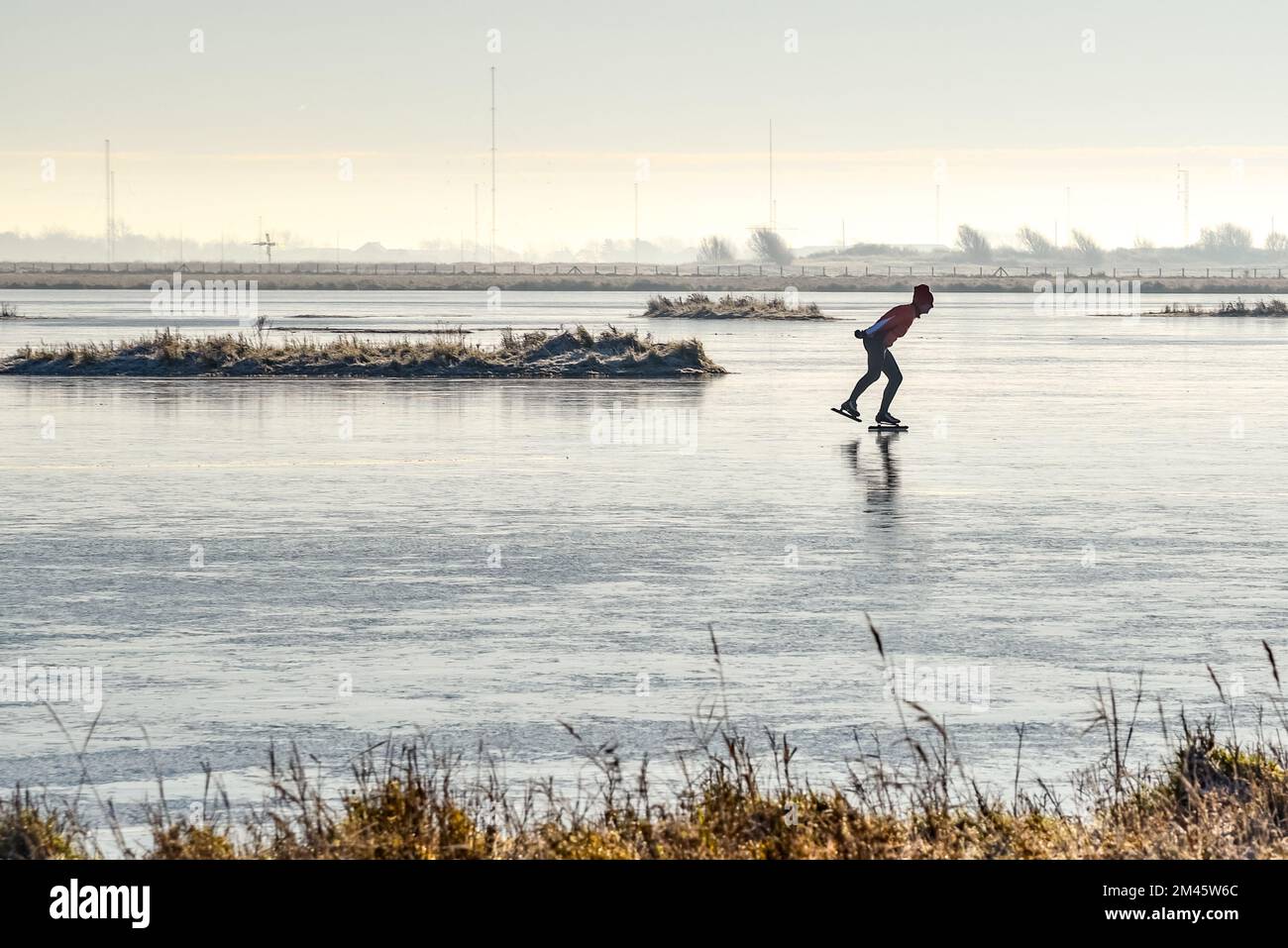 Den Helder, Niederlande. Dezember 2022. Einsame Schlittschuhläufer auf einem gefrorenen Teich in der Winterlandschaft in Holland. Hochwertiges Foto Stockfoto