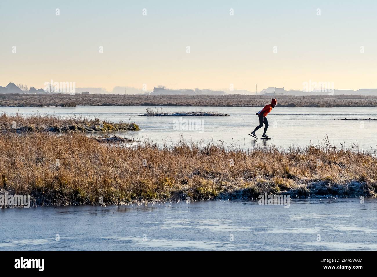 Den Helder, Niederlande. Dezember 2022. Einsame Schlittschuhläufer auf einem gefrorenen Teich in der Winterlandschaft in Holland. Hochwertiges Foto Stockfoto